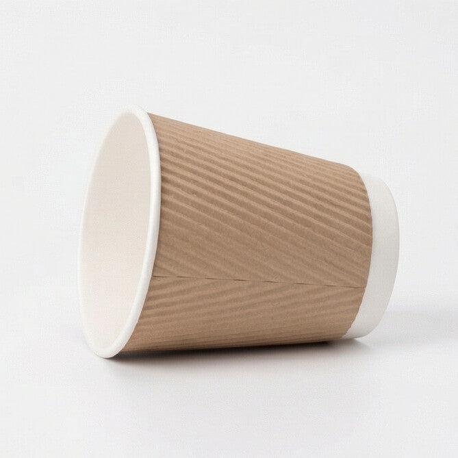 12oz kraft ripple wall paper cup tipped on its side on light grey, showing the white rim and ripple exterior from a low angle