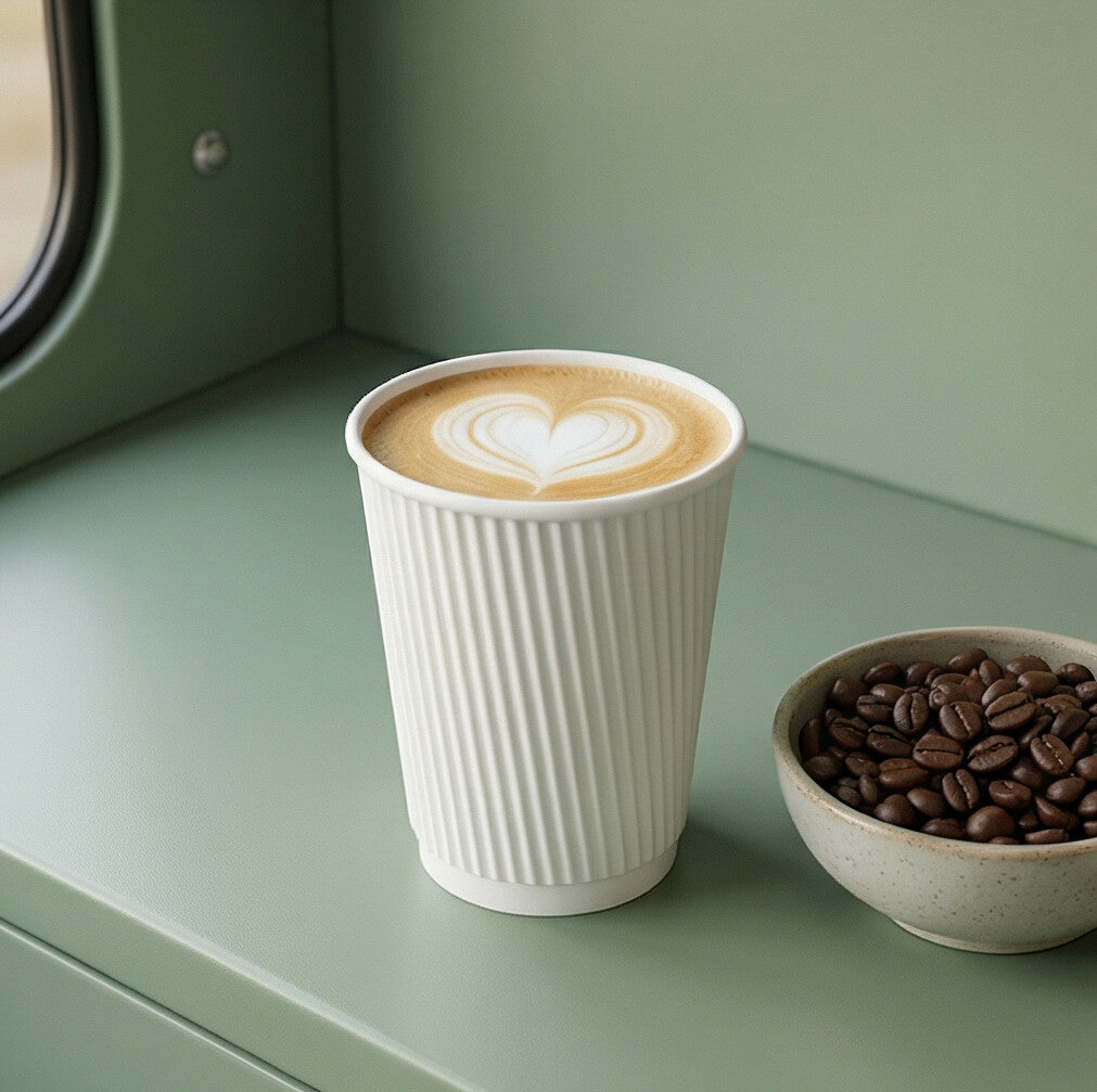 12oz White Ripple Wall Paper Cup with latte art heart on sage green café van counter, bowl of coffee beans beside
