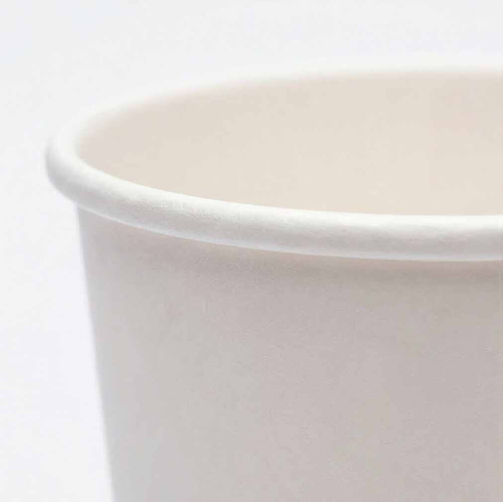 Extreme close-up of the rolled rim of a white 16oz paper cup from the left, showing fine paper texture on grey background