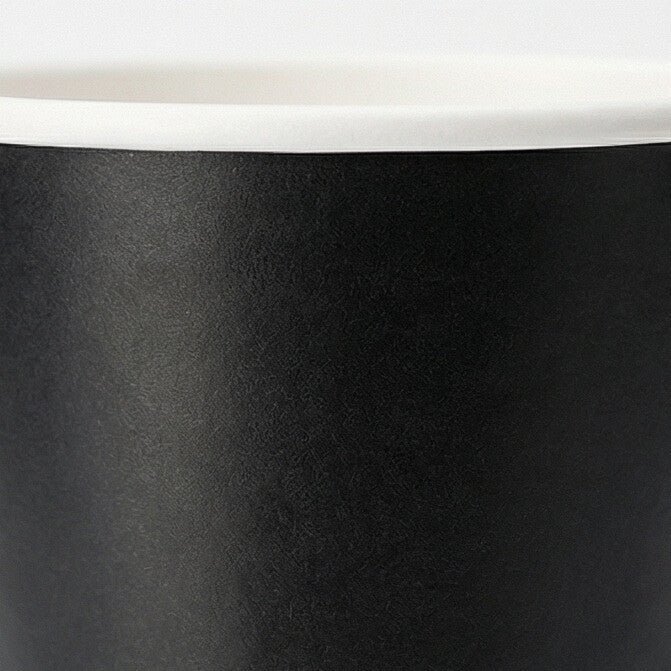 Extreme close-up of the matte black exterior surface and white rim of a 16oz double wall paper cup on white
