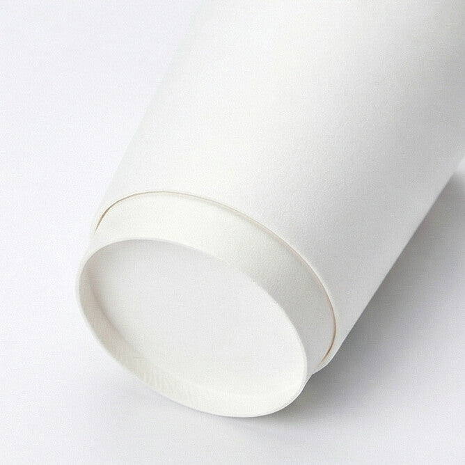 White 16oz double wall paper cup tipped on its side on white, showing the double-wall base ring and interior from a low angle