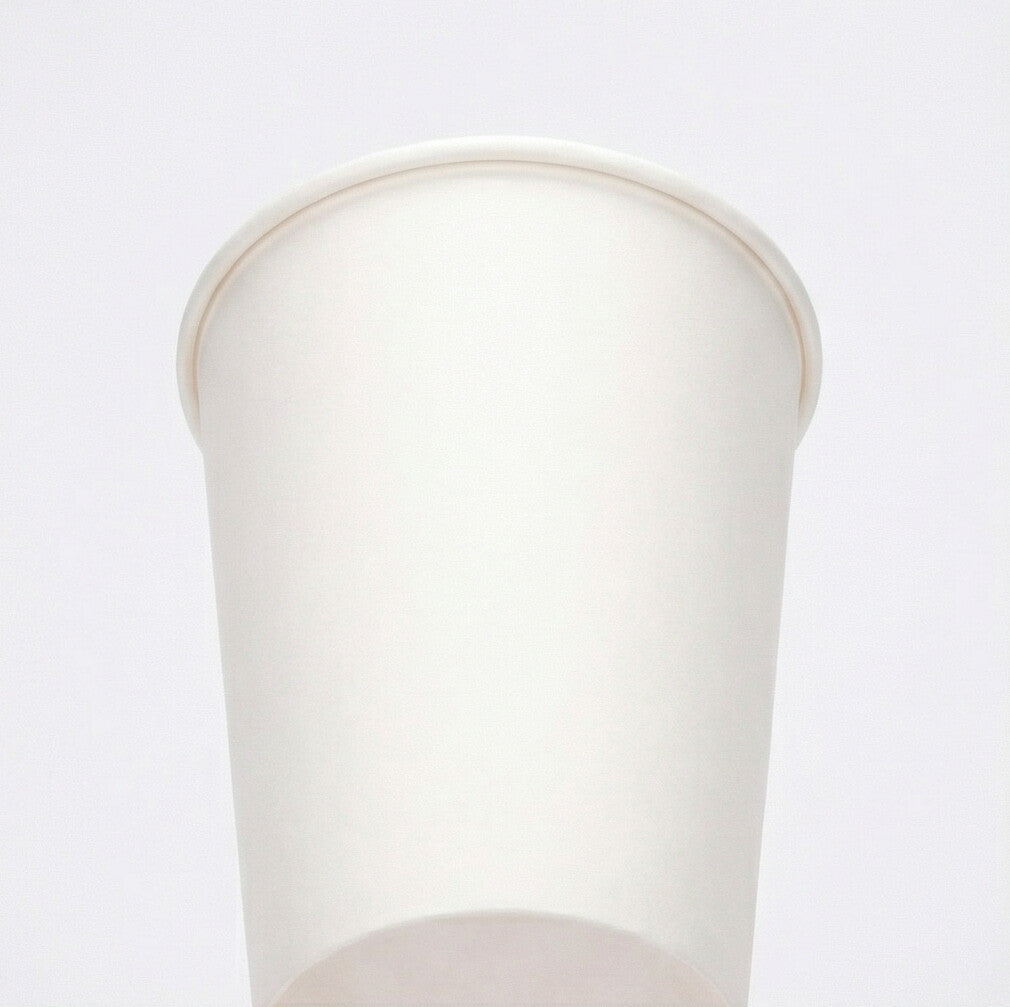 Low-angle shot looking up at a white 16oz paper cup, showing the tall exterior body and rolled rim on a light grey background