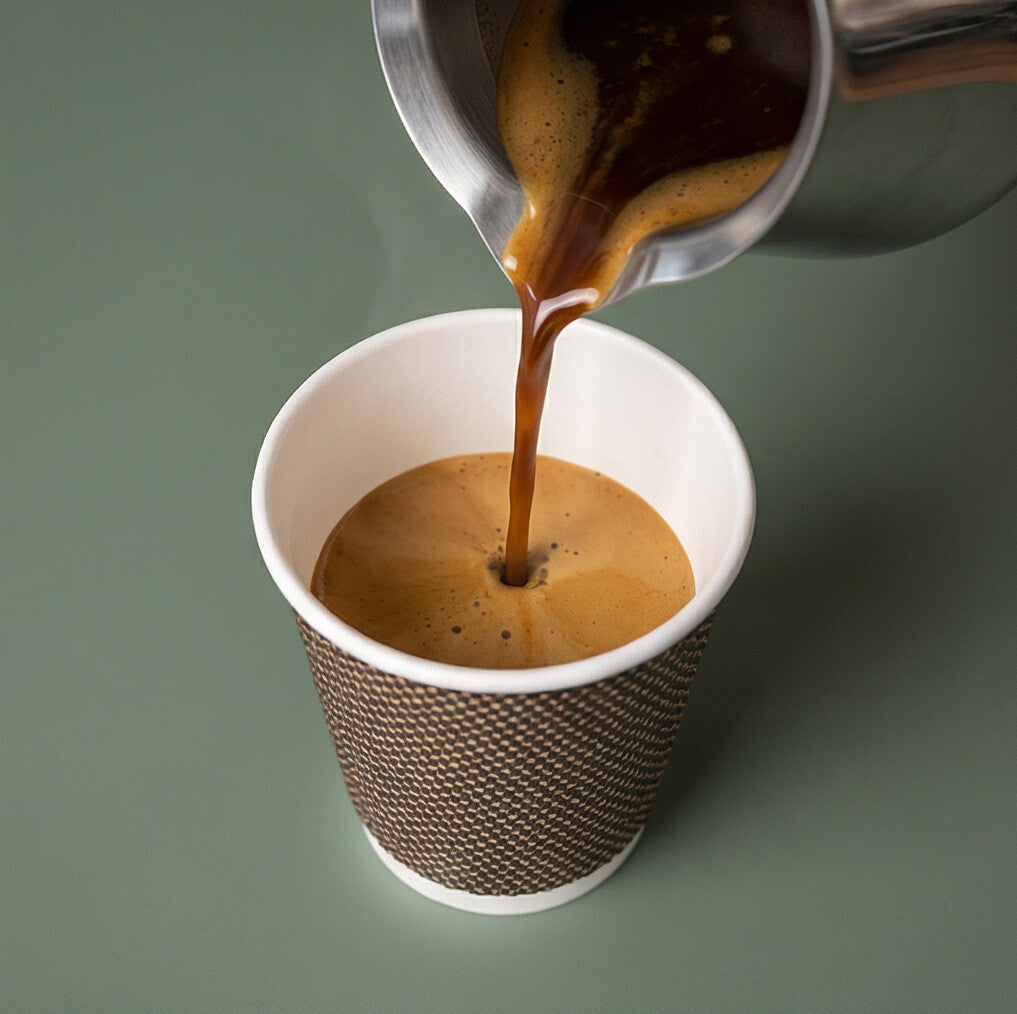 Espresso poured from a stainless steel jug into a 4oz VIP Ripple Wall Paper Cup, sage green background