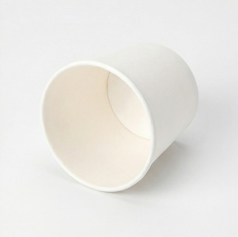 White single wall paper cup tipped on its side, showing the circular interior and base against a white background