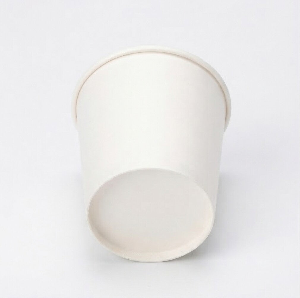 Very low angle shot of a white single wall paper cup from below, highlighting the flat base circle and tapered sides on white