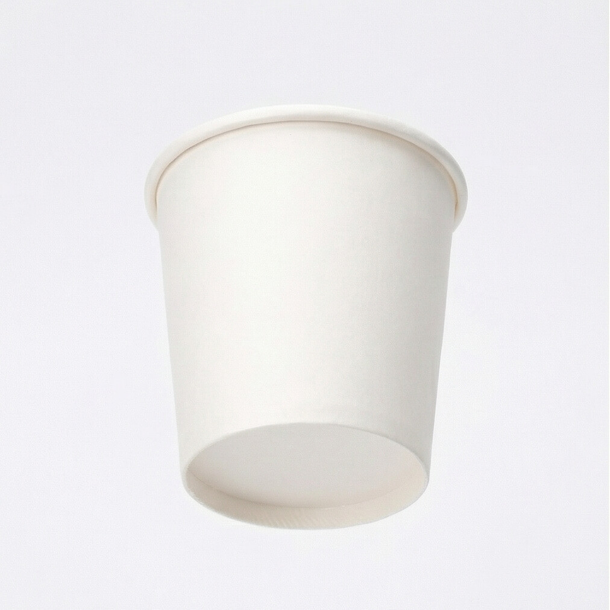 Low-angle front shot of a white single wall paper cup on a light grey background, emphasising the tapered body and base
