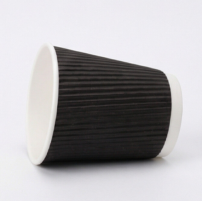 8oz black ripple wall paper cup tipped on its side on light grey, showing the black ripple exterior and white base ring