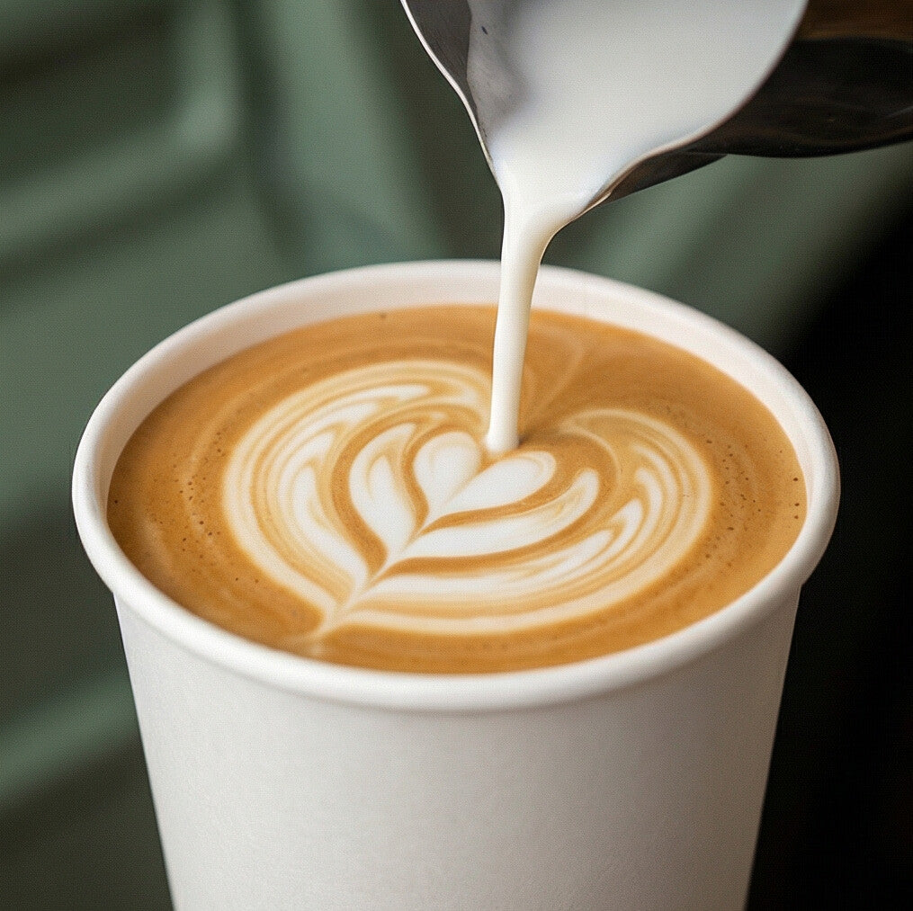 Steamed milk poured into an 8oz White Compostable Single Wall Paper Cup forming latte art heart, dark green background