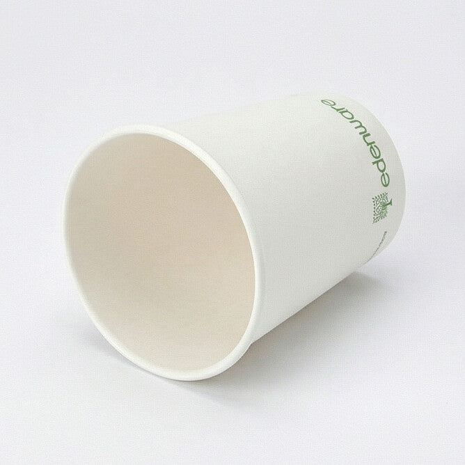 8oz white compostable single wall paper cup tipped on its side showing the interior and green-printed exterior, light grey