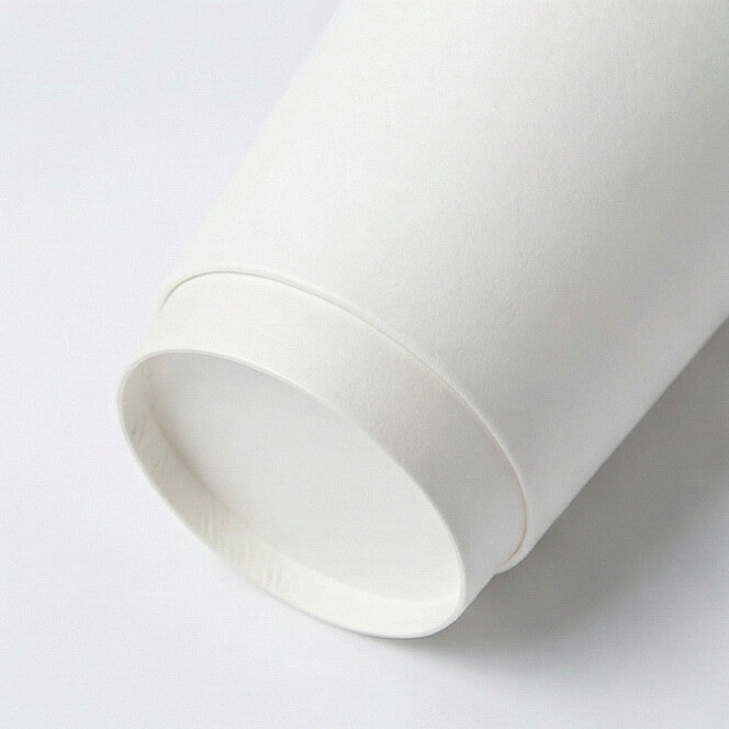 White 8oz double wall paper cup tipped on its side on white, showing the base ring and interior opening from a low angle