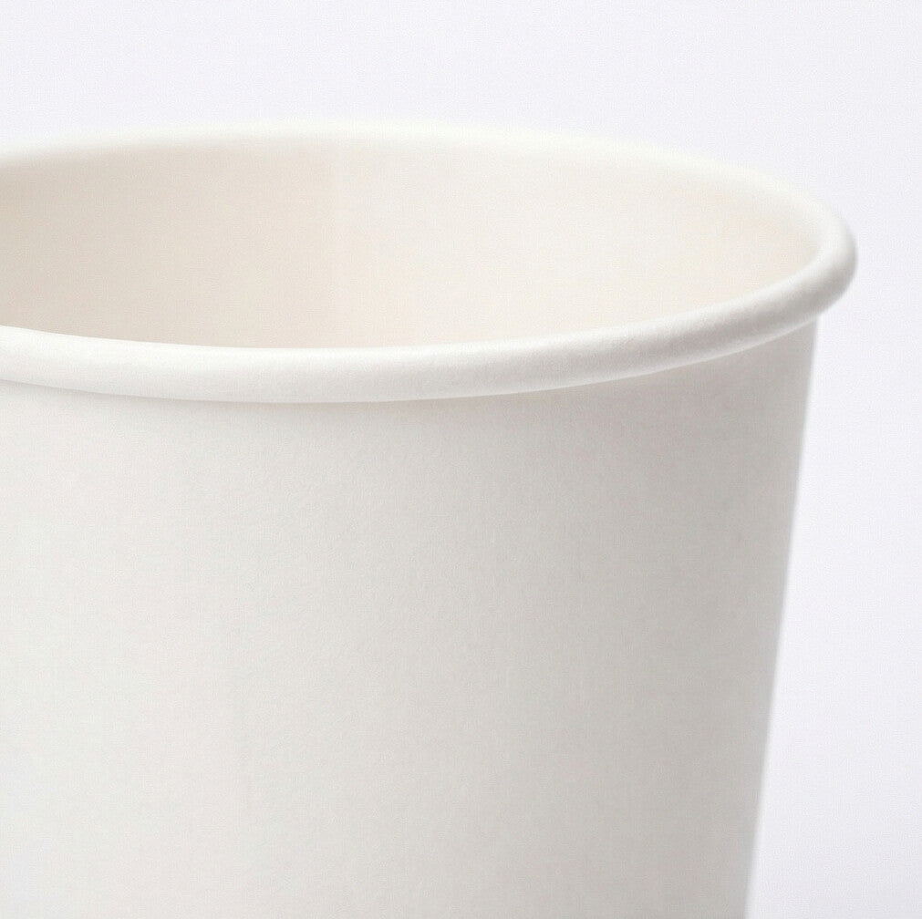 Extreme close-up of the rolled rim and interior of a white 8oz paper cup, showing paper texture and smooth sidewall on grey