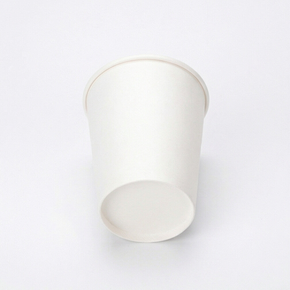 White single wall paper cup tipped on its side on a light grey background, exposing the flat base circle and interior