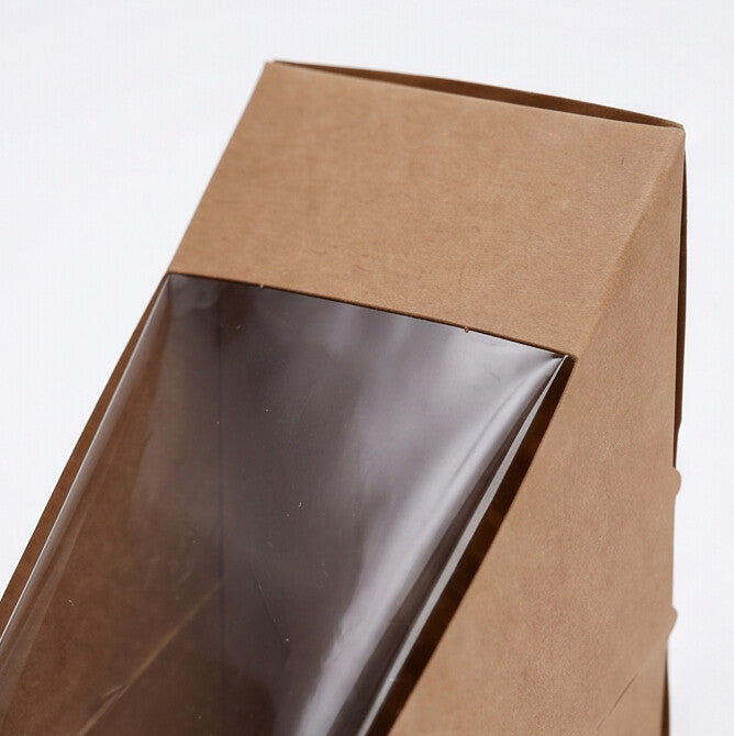 Kraft sandwich wedge deep fill box, close-up view of lower clear plastic display window and triangular base showing natural kraft brown board construction on white background