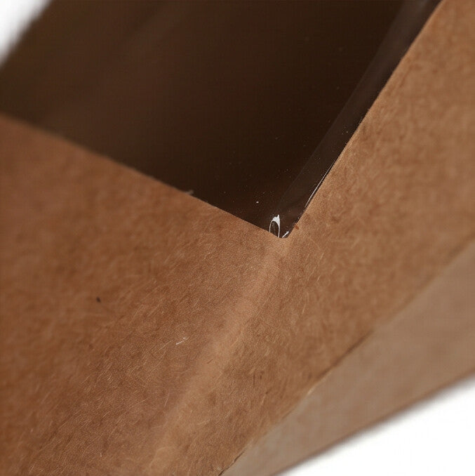 Kraft sandwich wedge box, extreme close-up detail of clear plastic window corner and kraft brown board construction showing material quality on white background