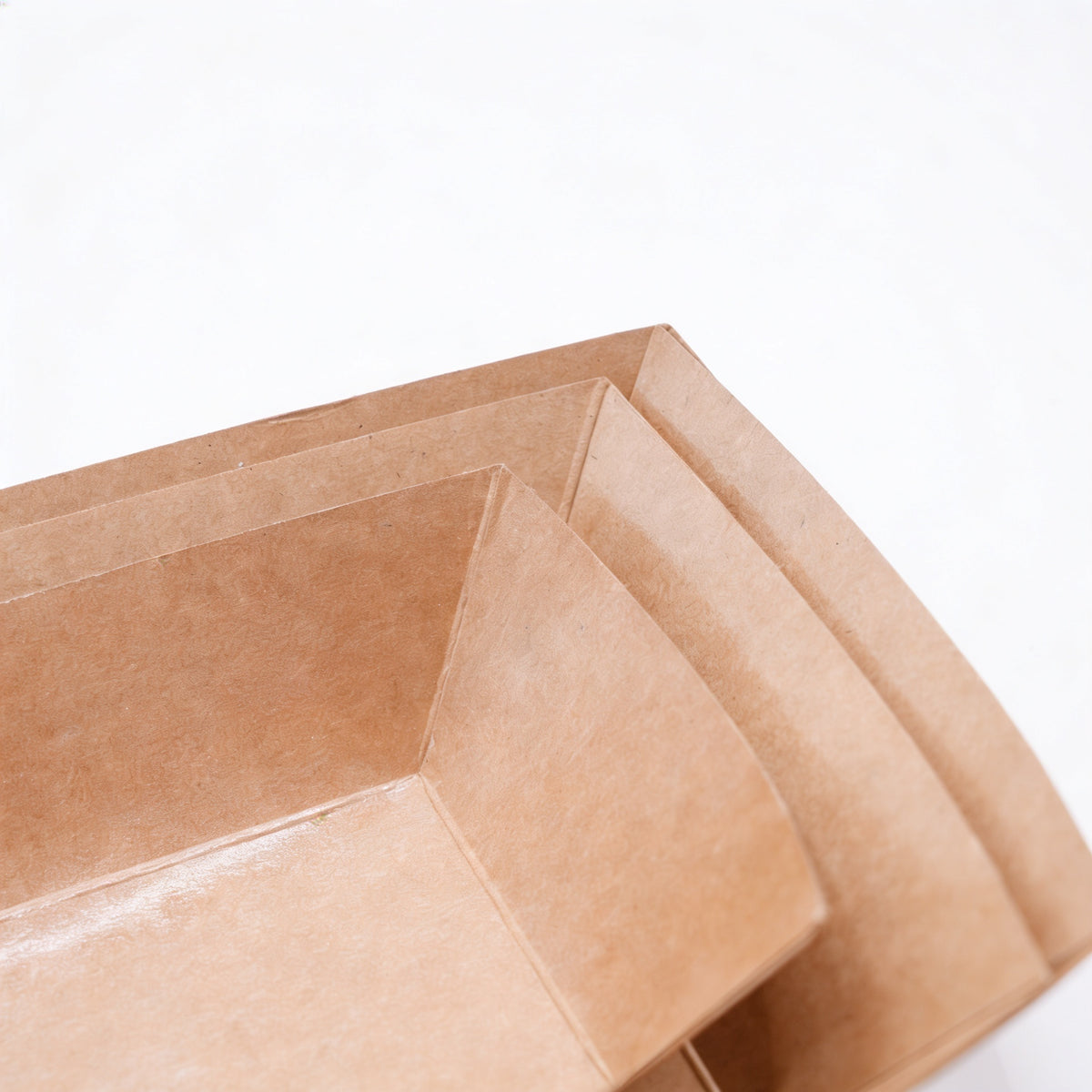 Medium kraft paper boat trays stacked, three-quarter angle view showing multiple nested trays and natural kraft brown construction on white background