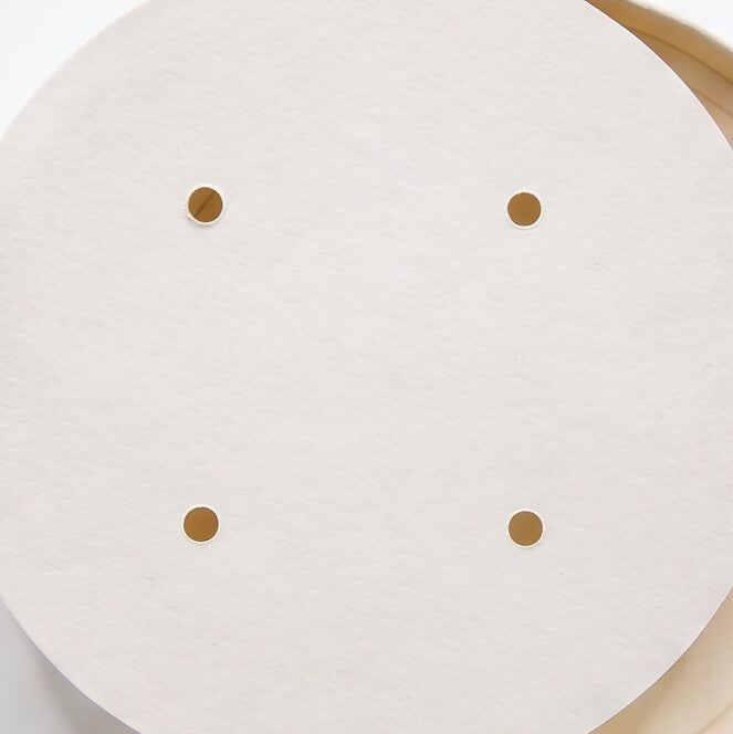 Close-up top view of white paper vented lid 98mm highlighting four ventilation holes for steam release